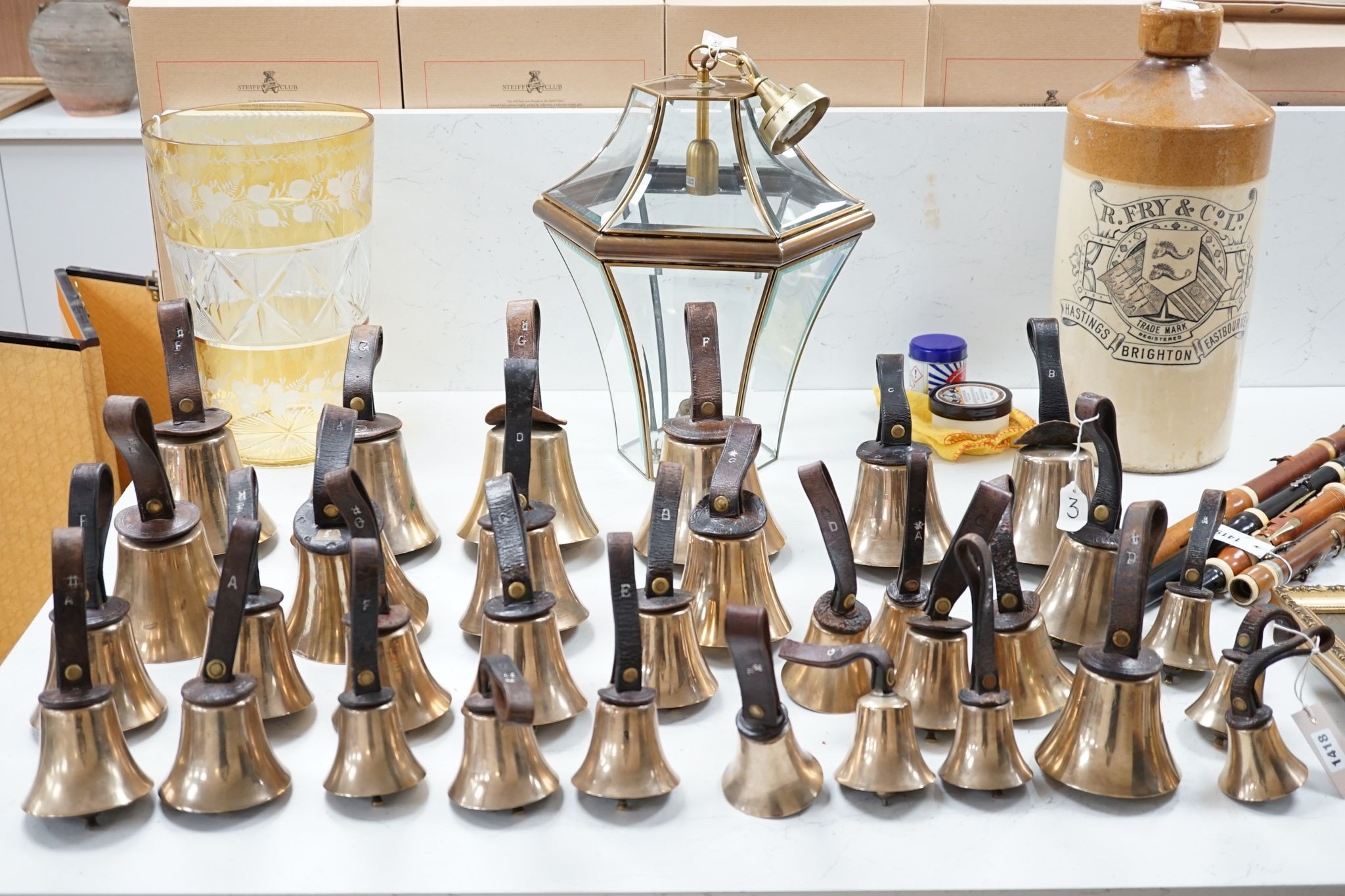 A rare set of 32 Whitechapel musical handbells, full chromatic scale, circa 1900, largest 23cm, including leather strap.